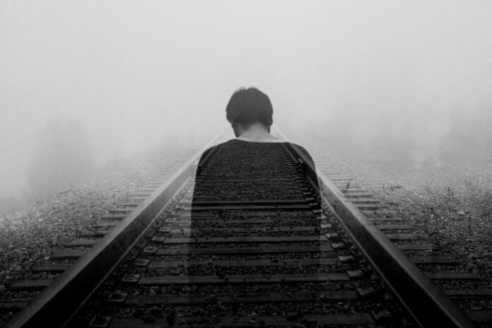 Man alone on train tracks photo by Gabriel / Unsplash, featured on Survivor Lit, a literary magazine for sexual assault survivors